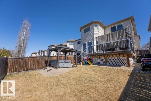 Expansive backyard featuring a hot tub with an accompanying gazebo, a wood privacy fence, and a multi-level deck with white lattice skirting - 1734 63A Street, Edmonton, AB - Outdoor With Deck Patio Veranda