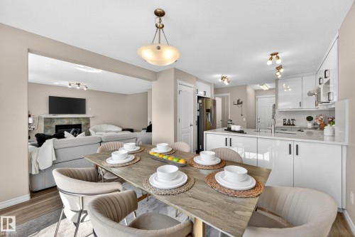 Open-concept dining area featuring a contemporary chandelier, wood-finish flooring, and a stone-look tabletop - 7723 7A Avenue, Edmonton, AB - Indoor Photo Showing Dining Room