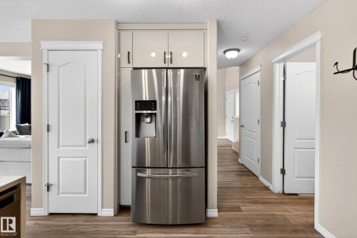 Stainless steel French door refrigerator with ice and water dispenser, integrated into custom cabinetry - 7723 7A Avenue, Edmonton, AB - Indoor