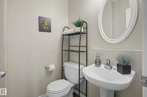 Pedestal sink with chrome faucet and an oval-framed mirror - 7723 7A Avenue, Edmonton, AB - Indoor Photo Showing Bathroom