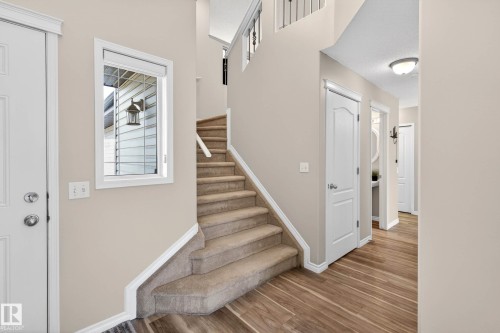 Foyer with wood-finish flooring, a carpeted staircase with a white handrail, and a window featuring a white blind - 7723 7A Avenue, Edmonton, AB - Indoor Photo Showing Other Room