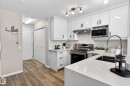Contemporary kitchen featuring white cabinetry, light-toned countertops, wood-finish flooring, a stainless steel sink with a high-arc faucet, and modern track lighting - 7723 7A Avenue, Edmonton, AB  - Indoor Photo Showing Kitchen With Upgraded Kitchen 