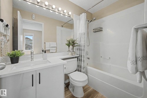 Bathroom featuring a white vanity with an integrated sink, light-colored countertop, and matte black hardware - 7723 7A Avenue, Edmonton, AB - Indoor Photo Showing Bathroom