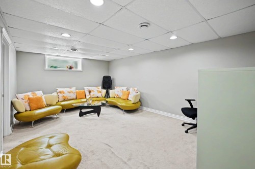 Spacious room featuring light gray walls, white trim, and a drop ceiling with recessed lighting - 7723 7A Avenue, Edmonton, AB - Indoor