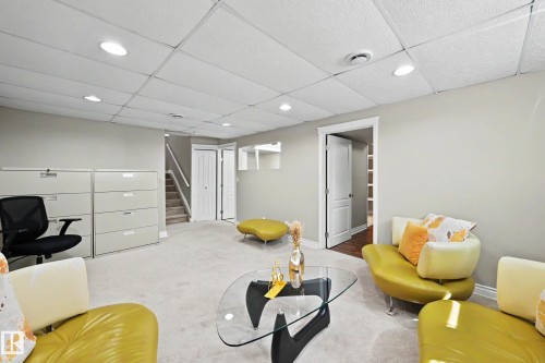 Spacious carpeted room featuring a drop ceiling with recessed lighting, light-toned wall paint, and white trim - 7723 7A Avenue, Edmonton, AB - Indoor
