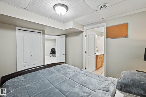Bedroom featuring neutral wall paint, recessed lighting, white bi-fold closet doors, and access to an additional room and a bathroom with wood-finish cabinetry - 7723 7A Avenue, Edmonton, AB - Indoor Photo Showing Bedroom
