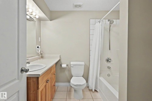 Full bathroom featuring a single vanity with wood cabinetry, a light-toned countertop, and a white drop-in sink - 7723 7A Avenue, Edmonton, AB - Indoor Photo Showing Bathroom