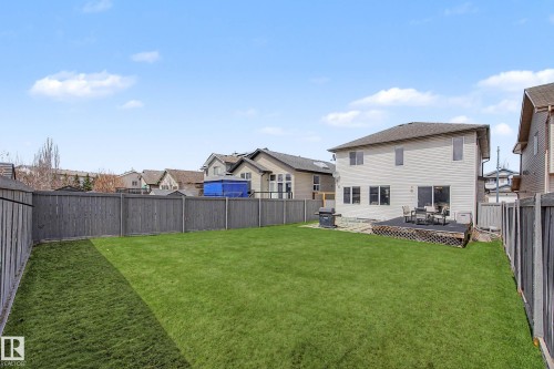 Expansive backyard featuring a manicured lawn, full privacy fencing, and a wooden deck - 7723 7A Avenue, Edmonton, AB - Outdoor