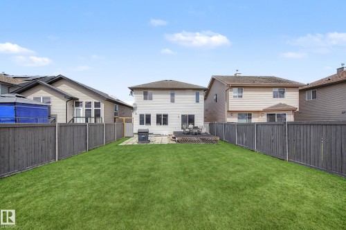 Expansive backyard featuring a large lawn area, full privacy fencing, a wood deck, and a paved patio - 7723 7A Avenue, Edmonton, AB - Outdoor