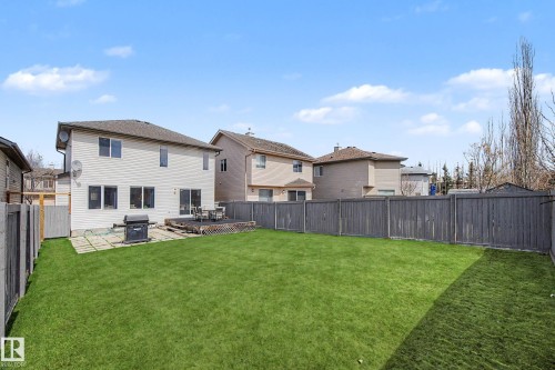 Expansive backyard featuring a large green lawn, a wooden deck, and a patio area - 7723 7A Avenue, Edmonton, AB - Outdoor With Backyard