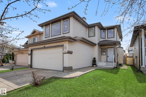 Two-story residence featuring light-colored siding, a covered front entry, and a two-car garage with a concrete driveway - 7723 7A Avenue, Edmonton, AB - Outdoor
