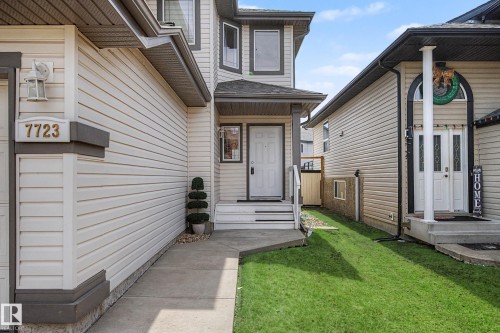 Exterior featuring light-colored siding, a covered front entry with white steps, a concrete walkway, and a green lawn strip - 7723 7A Avenue, Edmonton, AB - Outdoor With Exterior