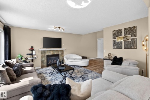Living area featuring a tiled fireplace with a white mantel, recessed lighting, and wood-finish flooring extending into the background - 7723 7A Avenue, Edmonton, AB - Indoor Photo Showing Living Room With Fireplace