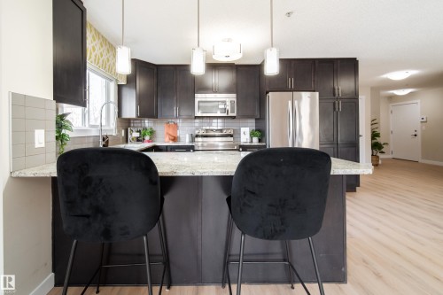 Contemporary kitchen featuring dark wood cabinetry, stainless steel appliances, and a light-toned countertop - 117 2229 44 Avenue, Edmonton, AB - Indoor Photo Showing Kitchen With Stainless Steel Kitchen With Upgraded Kitchen