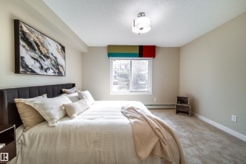 Bedroom featuring neutral wall paint, light-toned carpet, a window with a valance, and a ceiling-mounted light fixture - 117 2229 44 Avenue, Edmonton, AB - Indoor Photo Showing Bedroom