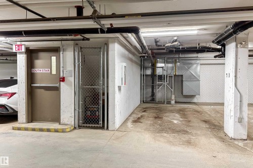 Underground parking space with concrete flooring, exposed ceiling pipes, and a security fence - 117 2229 44 Avenue, Edmonton, AB - Indoor Photo Showing Garage