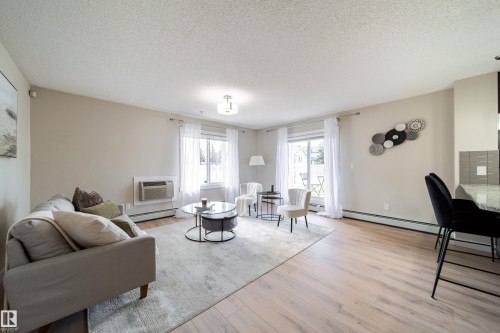 Open-concept living area featuring light wood-finish flooring, light neutral wall paint, and a sliding glass door leading to an outdoor space - 117 2229 44 Avenue, Edmonton, AB - Indoor Photo Showing Living Room