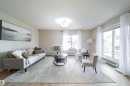 Bright living area featuring wood-finish flooring, light-colored walls, and a large window with a sliding glass door - 117 2229 44 Avenue, Edmonton, AB  - Indoor Photo Showing Living Room 