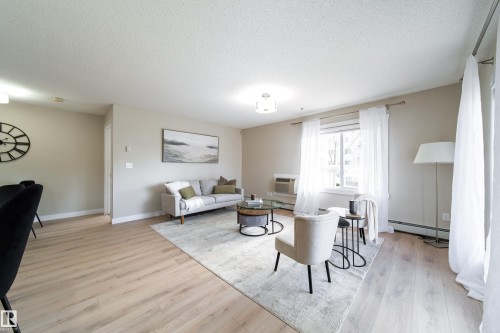 Spacious open-concept living area featuring light wood-finish flooring, neutral paint palette, and ample natural light from a large window - 117 2229 44 Avenue, Edmonton, AB - Indoor Photo Showing Living Room