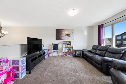 Spacious upper-level room featuring large windows with dark trim, a neutral carpet, and recessed lighting - 6115 18 Avenue, Edmonton, AB - Indoor Photo Showing Living Room