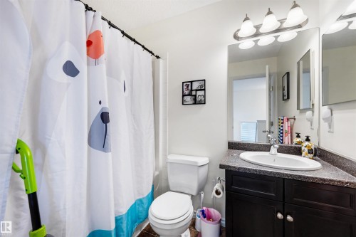 Bathroom featuring a dark wood-finish vanity with a speckled countertop and an undermount sink - 6115 18 Avenue, Edmonton, AB - Indoor Photo Showing Bathroom