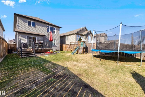 Expansive backyard featuring a wood deck with railings, a sliding glass door entry, and gray vinyl siding - 6115 18 Avenue, Edmonton, AB - Outdoor With Deck Patio Veranda