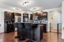 Spacious kitchen featuring dark wood cabinetry, stainless steel appliances, a large island with counter seating, and wood-finish flooring - 6115 18 Avenue, Edmonton, AB  - Indoor Photo Showing Kitchen With Upgraded Kitchen 