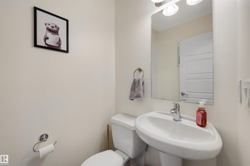 Pedestal sink with chrome faucet, mirror, and integrated vanity lighting - 6115 18 Avenue, Edmonton, AB - Indoor Photo Showing Bathroom