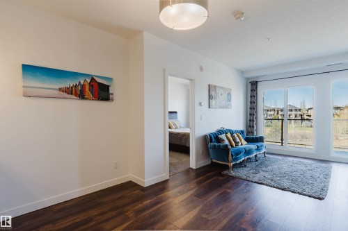 Expansive room featuring wood-finish flooring, white baseboards, and bright white walls - 205 1316 Windermere Way, Edmonton, AB - Indoor