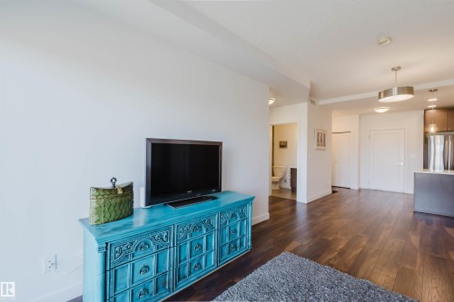 Rich wood-finish flooring extends throughout this open-concept area - 205 1316 Windermere Way, Edmonton, AB - Indoor
