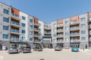 Modern multi-story building featuring a gray and white facade with red-brown accents - 205 1316 Windermere Way, Edmonton, AB  - Outdoor With Balcony With Facade 