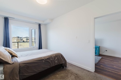 Bright room with a large window and white trim - 205 1316 Windermere Way, Edmonton, AB - Indoor Photo Showing Bedroom
