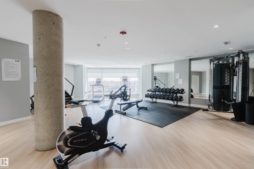 Fitness center featuring wood-finish flooring, a concrete pillar, full-height windows, recessed lighting, and mirrored walls - 205 1316 Windermere Way, Edmonton, AB - Indoor Photo Showing Gym Room