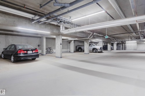 Underground parking garage featuring concrete flooring and walls - 205 1316 Windermere Way, Edmonton, AB - Indoor Photo Showing Garage