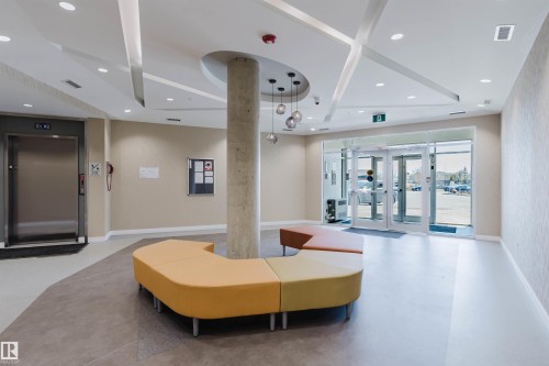 Lobby area featuring a stainless steel elevator, glass entry doors, recessed lighting, and a decorative ceiling with geometric accents - 205 1316 Windermere Way, Edmonton, AB - Indoor Photo Showing Other Room