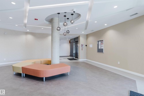 Lobby area featuring light gray flooring, textured accent walls, and recessed lighting - 205 1316 Windermere Way, Edmonton, AB - Indoor Photo Showing Other Room