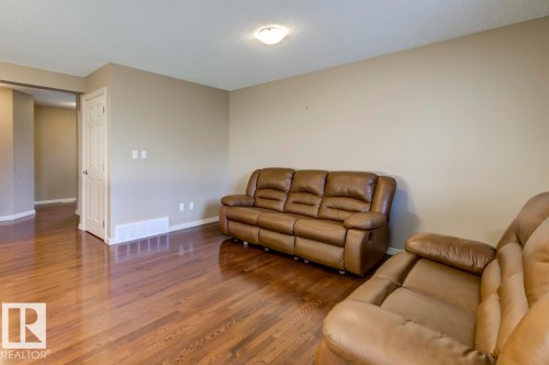 Spacious room featuring wood-finish flooring, neutral wall tones, and white trim - 119 Rue Monique, Beaumont, AB - Indoor Photo Showing Living Room