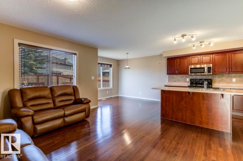 Open-concept living space featuring rich wood-finish flooring throughout - 119 Rue Monique, Beaumont, AB - Indoor Photo Showing Kitchen