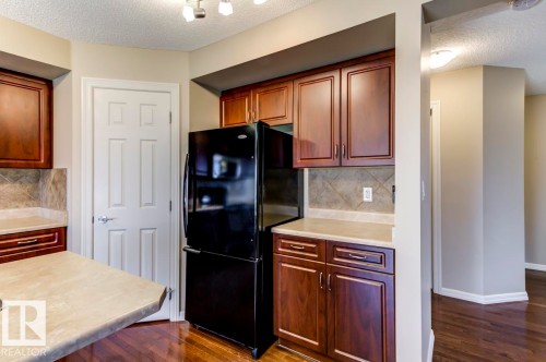 Kitchen featuring dark wood cabinetry, light countertops, and a tiled backsplash - 119 Rue Monique, Beaumont, AB - Indoor Photo Showing Kitchen