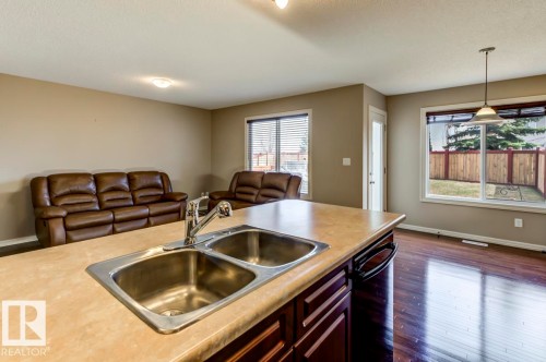 Kitchen island with a double basin stainless steel sink and chrome faucet - 119 Rue Monique, Beaumont, AB - Indoor Photo Showing Kitchen With Double Sink