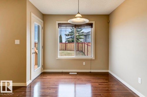 Room with wood-finish flooring, a pendant light fixture, and neutral painted walls - 119 Rue Monique, Beaumont, AB - Indoor Photo Showing Other Room