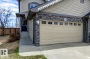 Cream-colored garage door with transom-style windows, complemented by stacked stone veneer accents - 119 Rue Monique, Beaumont, AB  - Outdoor 