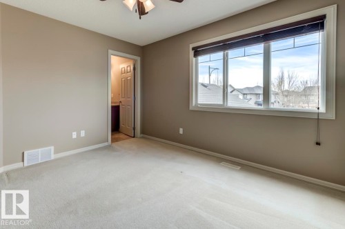 Carpeted room with a large multi-pane window, neutral wall paint, and a textured ceiling - 119 Rue Monique, Beaumont, AB - Indoor Photo Showing Other Room