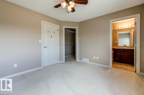Neutral-toned room featuring light-colored carpeting, a ceiling fan with light fixture, and two panel doors - 119 Rue Monique, Beaumont, AB - Indoor