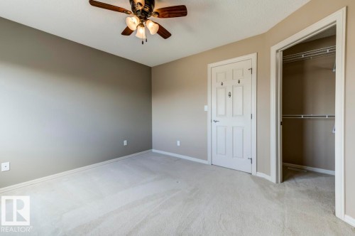 Carpeted room with a ceiling fan light fixture, neutral wall paint, white trim, and a white paneled door - 119 Rue Monique, Beaumont, AB - Indoor Photo Showing Other Room