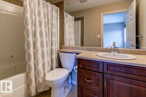 Bathroom featuring a white bathtub, toilet, and a vanity with a dark wood-finish cabinet - 119 Rue Monique, Beaumont, AB - Indoor Photo Showing Bathroom