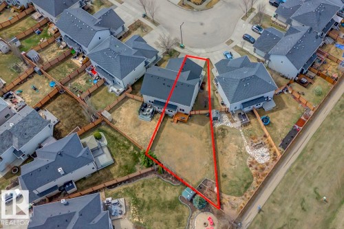 Expansive rear yard featuring a large grass area, decorative rock landscaping, and a wooden fence perimeter - 119 Rue Monique, Beaumont, AB - 