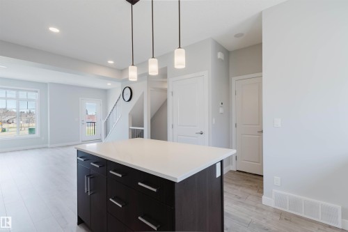 Kitchen island featuring a white countertop and dark wood-finish cabinetry with bar pull hardware - 3 11373 12 Avenue, Edmonton, AB - Indoor