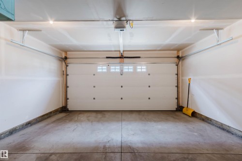 Garage featuring a concrete floor, white painted walls, and an overhead door with window panels - 3 11373 12 Avenue, Edmonton, AB - Indoor Photo Showing Garage