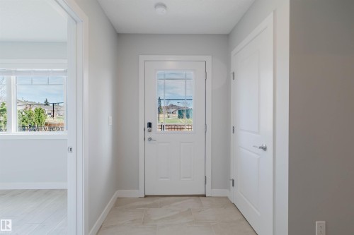Entryway featuring a white paneled door with glass inserts, smart lock hardware, and light-toned tile flooring - 3 11373 12 Avenue, Edmonton, AB - Indoor Photo Showing Other Room